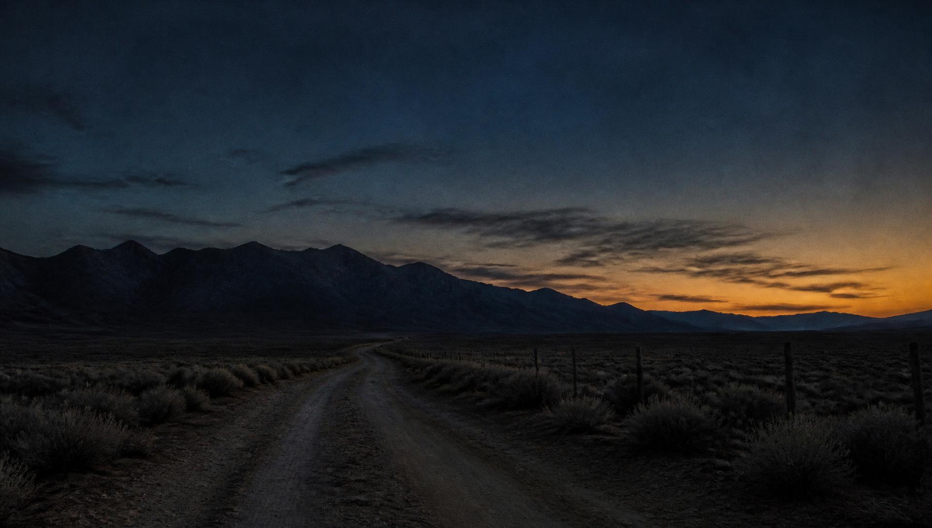 Dirt road running toward a dark mountain ridge at dusk